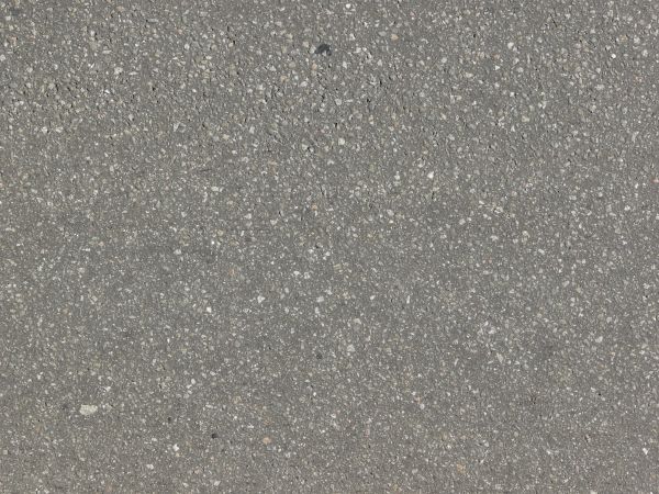 Rough asphalt surface in dark grey tone with embedded stones throughout.